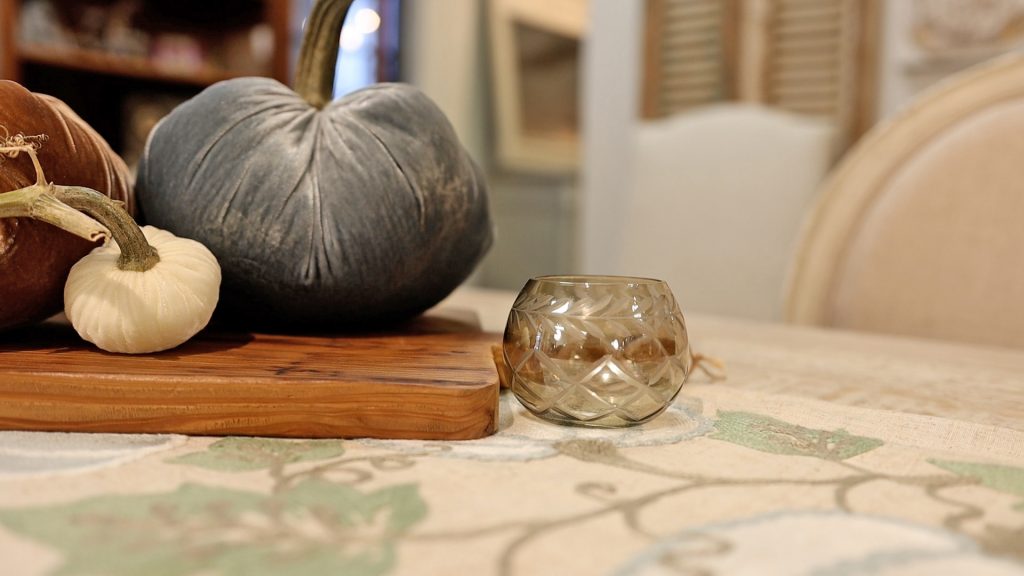 To add some lighting to her simple farmhouse fall table makeover, Amitha Verma adds a single smoky glass votive where a tealight candle can be placed.