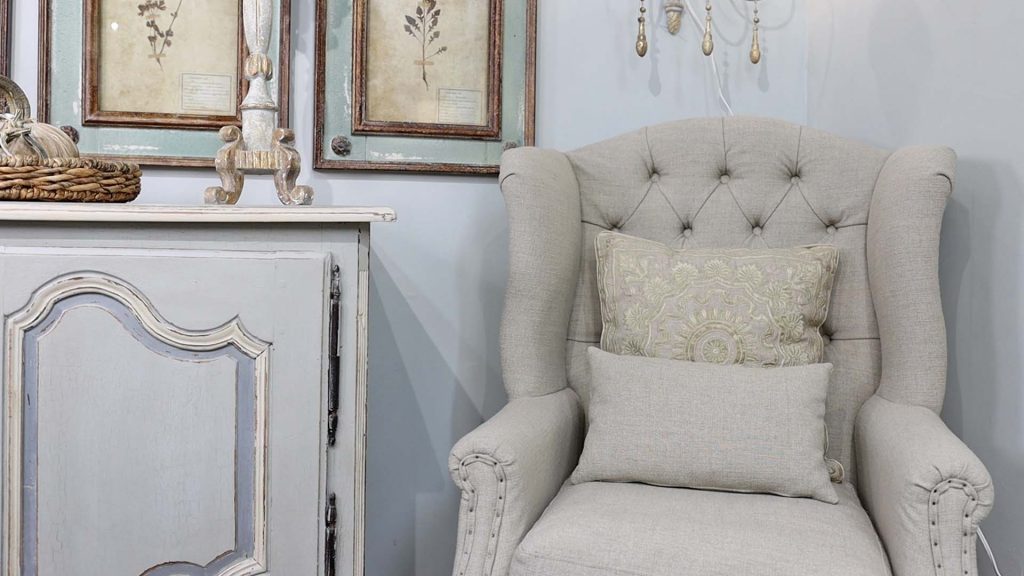 A styled vignette corner at Village Antiques that highlights French country decor throw pillows, styled by Amitha Verma.
